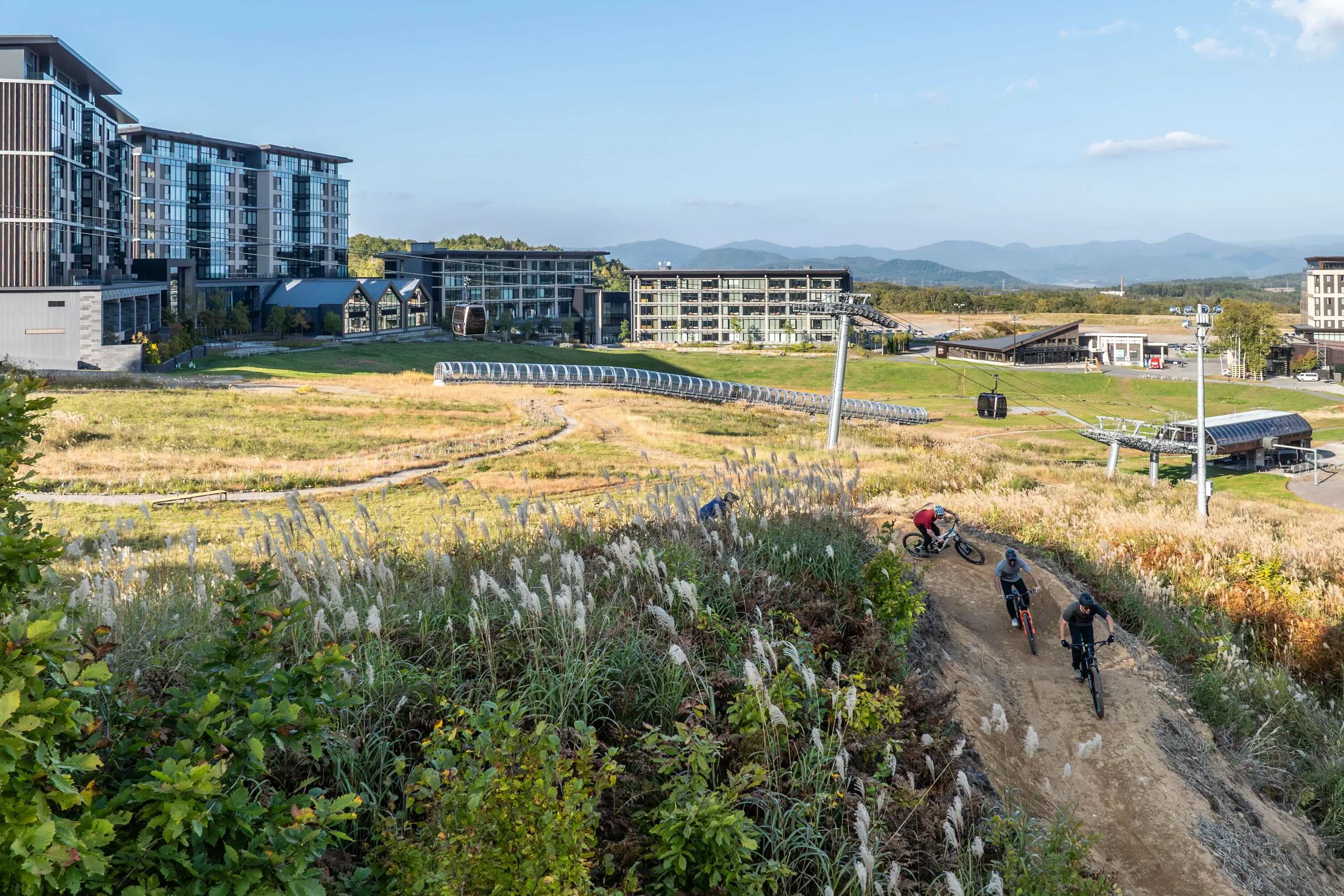 Mountain bikers rounding a berm with hotels behind