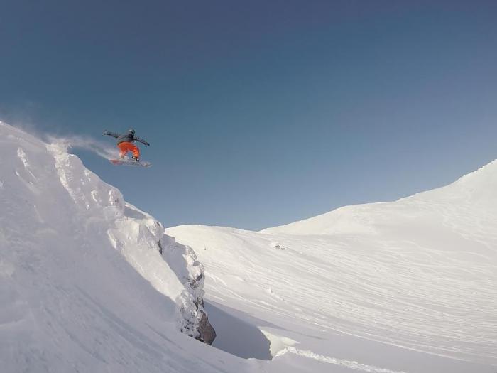 A snowboarder gets air over a cliff