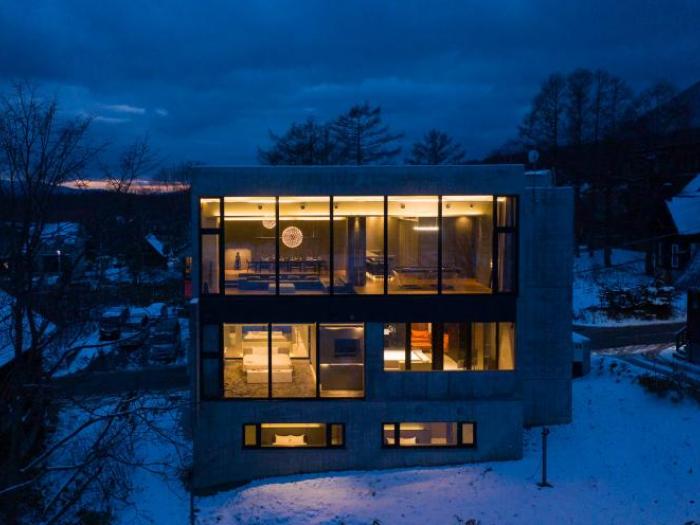A large 3 story concrete home lit from the inside