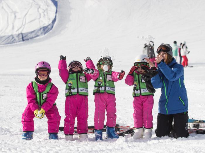 Children in pink suits throwing snow