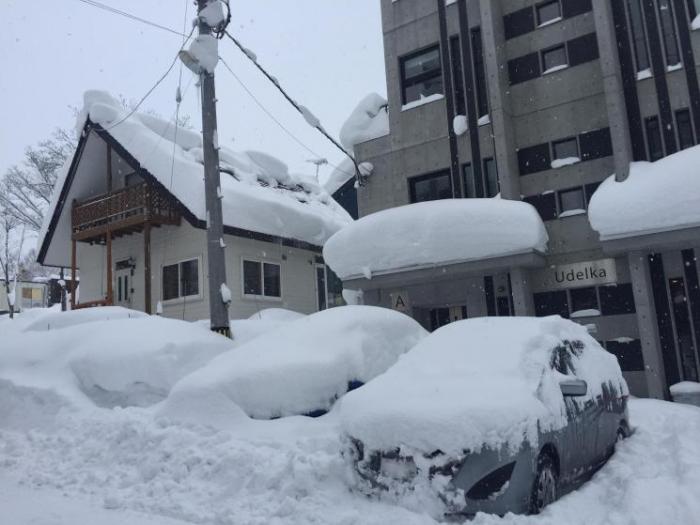 Cars and buildings in Hirafu smothered by snow.