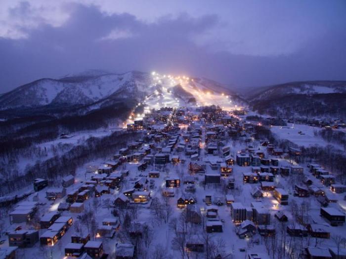 A night time photo of Hirafu village looking up to the lit up ski area
