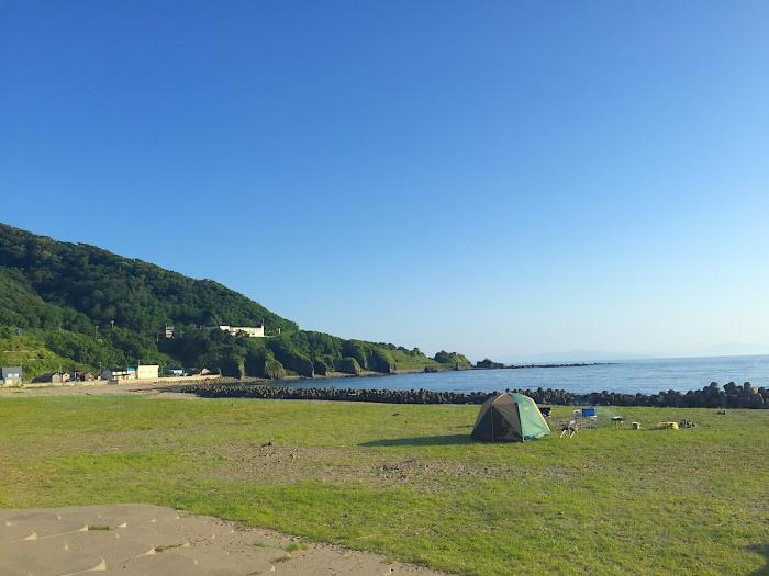 A tent pitched on green grass by the sea
