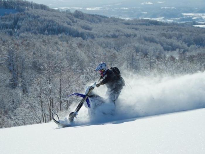 A snow bike does a deep turn in powder snow