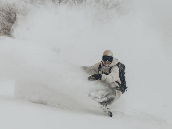 A snowboarder digging a deep powder turn