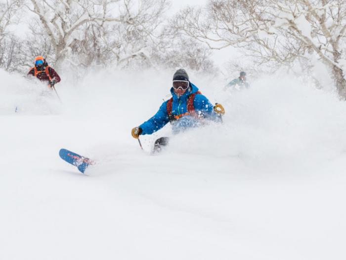 A skier makes a deep turn in powder snow.