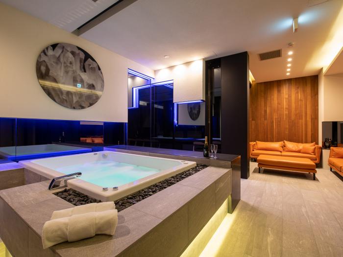A spa bath and orange lounge suite behind
