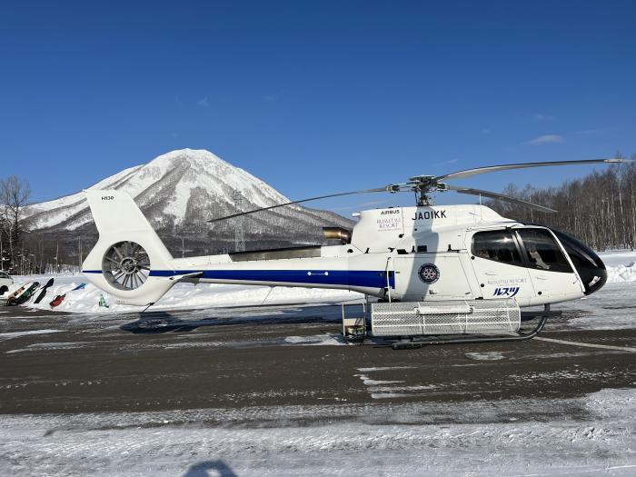A helicopter parked on the tarmac in front of Mount Shiribestu
