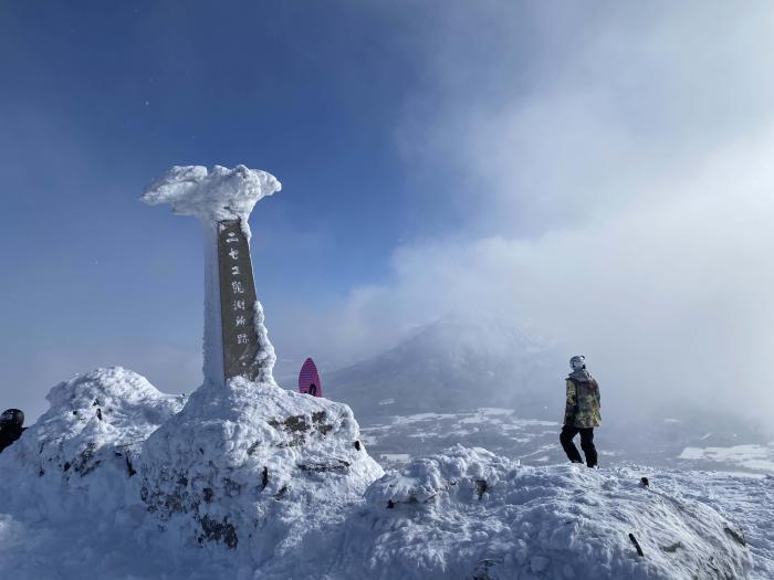 A snow crusted monument at the top of Mount Annupuri with Mount Yotei in the back ground.