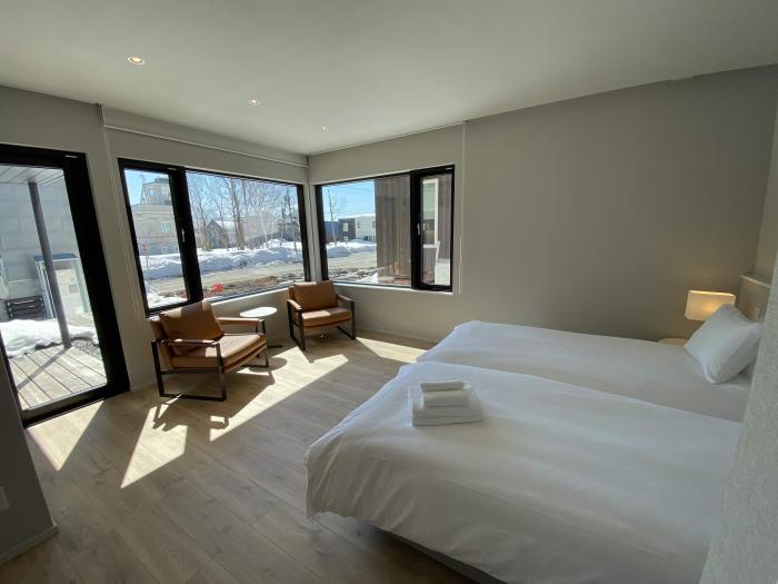 Aozora bedroom 2 A bedroom with white beds and chairs in a sunny corner