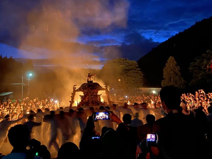 A portable shrine is back lit by fire at night