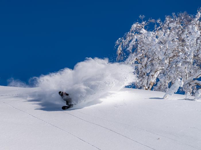 A snowboarder makes a turn in powder snow
