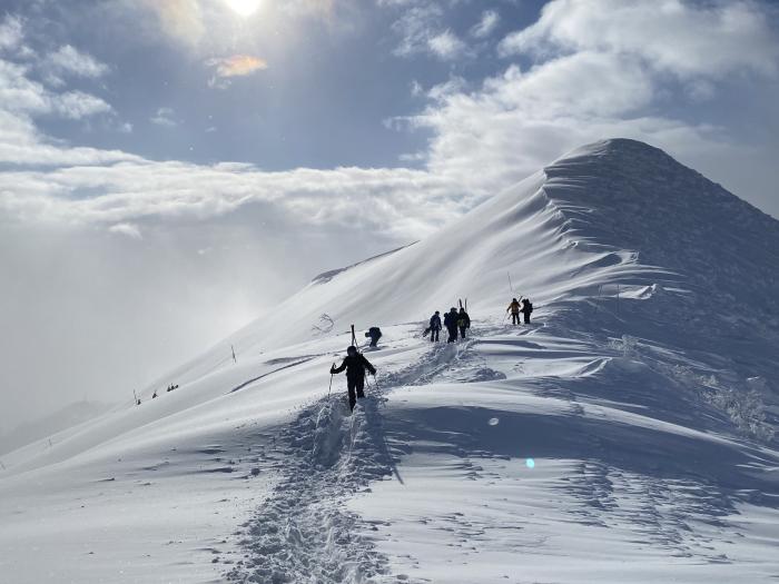 skiiers hiking up a snowy slope