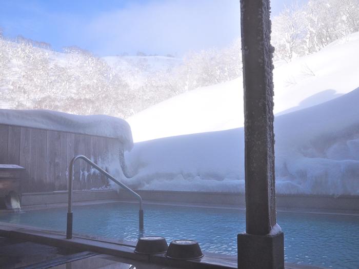 An outdoor onsen surrounded by snow.