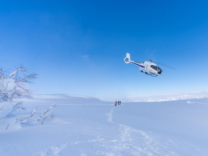 A helicopter makes a banked turn above the snow