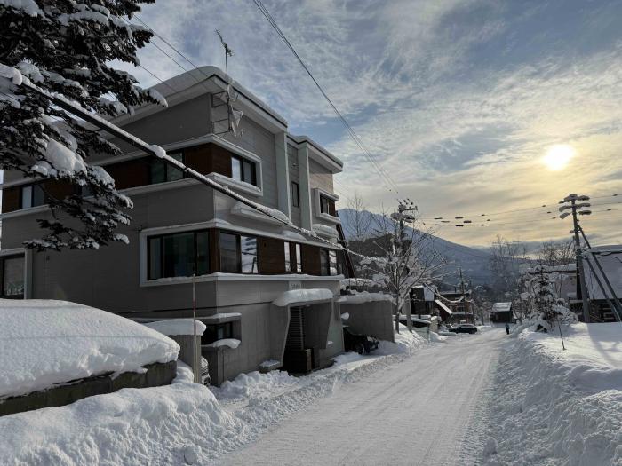 A snowy street with two story building to the left