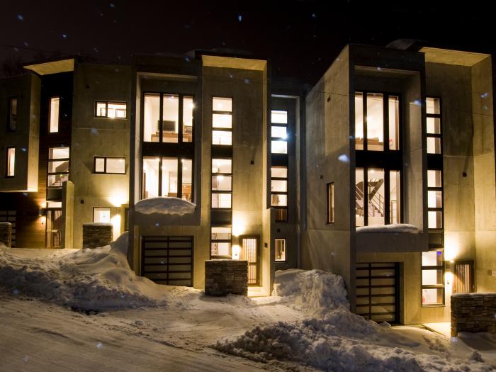 3 concrete town houses in snowy surrounds lit up at night