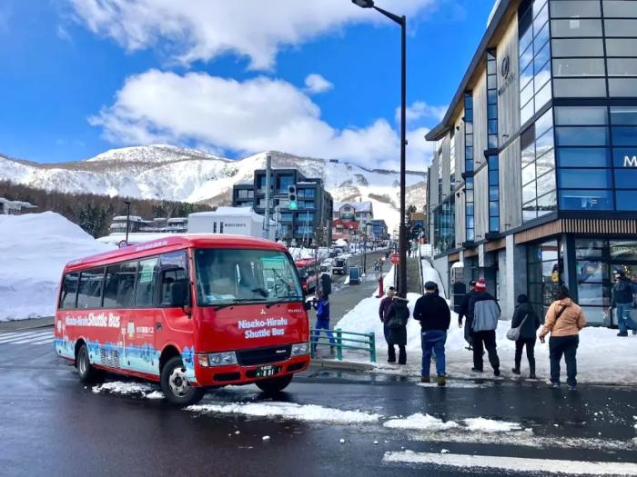 The red Hirafu shuttle bus turns a corner