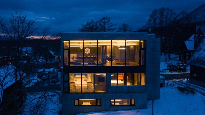 A large 3 story concrete home building lit up at night.