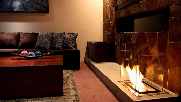 fireplace with black leather couches, stone faced wall, and wooden coffee table