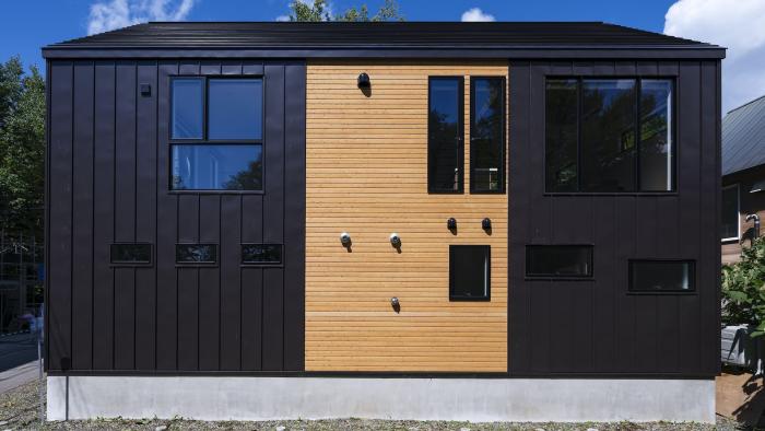 A two story house with black and wood coloured cladding