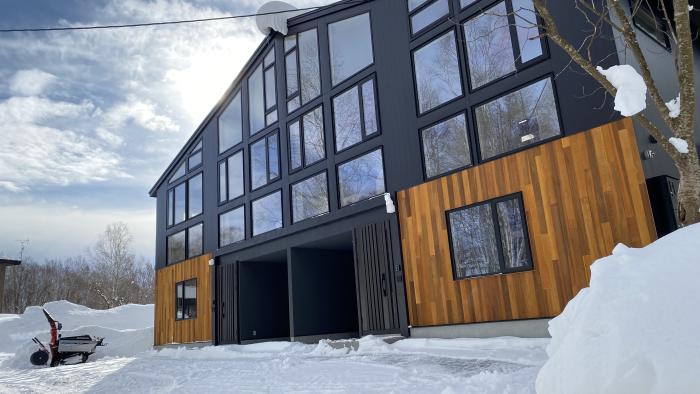 A two story duplex with 2 garages, striking wood and steel cladding and multiple windows.