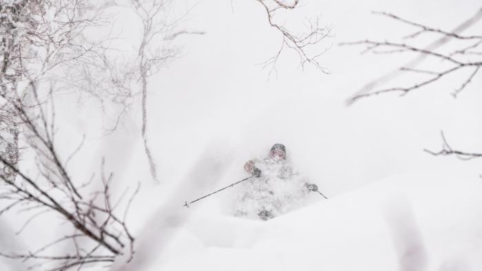 A skier makes a deep turn in powder snow