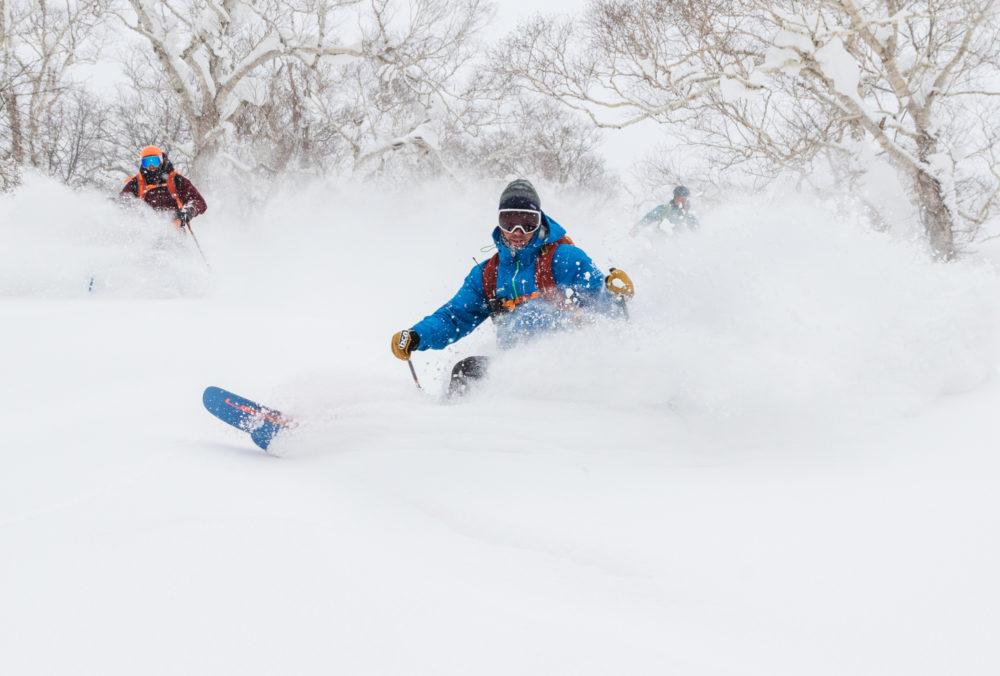 A skier makes a deep turn in powder snow