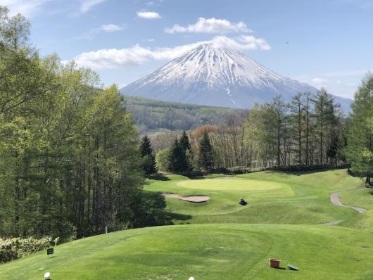 A well kept golf course green with a snow capped Mount Yotei in the back ground.