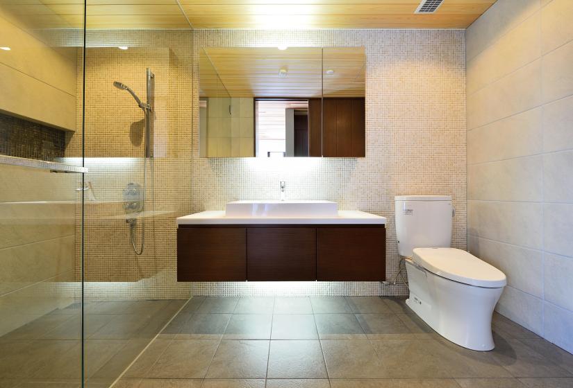 bathroom with shower with glass door and stone tiles