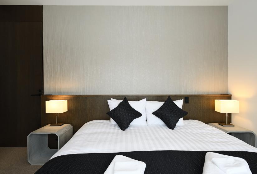 large bed with white sheets, black pillows, and lamps
