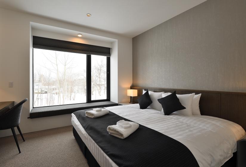 bedroom with large bed, bedside lamp, and large windows