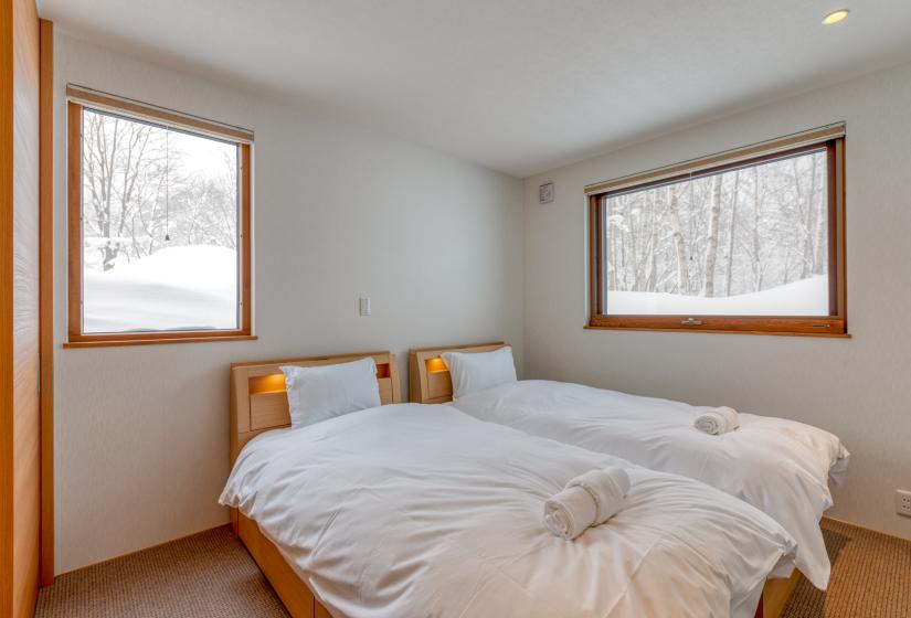 two single beds with windows and white walls