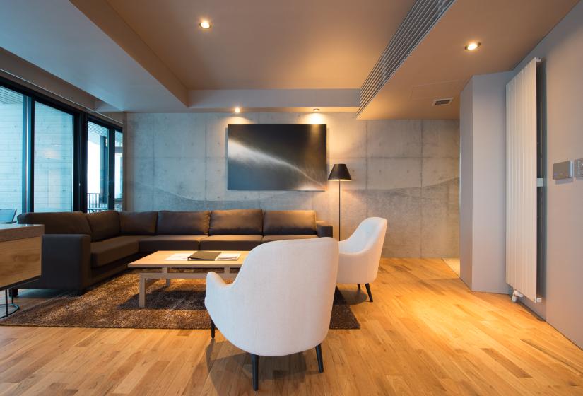 White arm chairs in lounge with corner sofa and wall TV