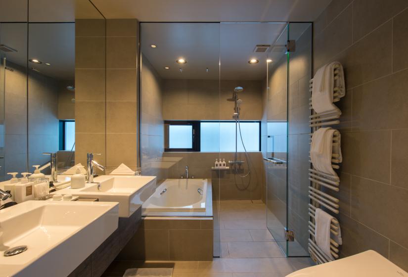 Bath tub & shower at back with 2 vanity sinks with fall wall mirror at front