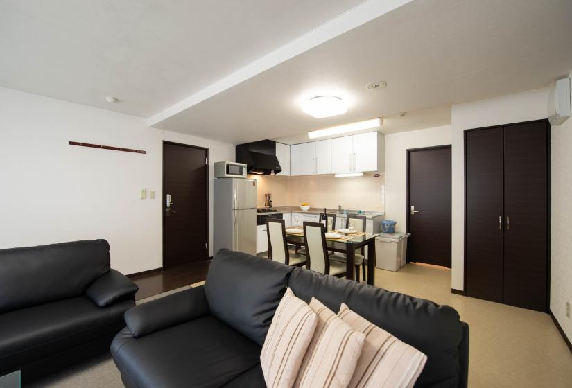 black sofa with three cushions with dining table in the background