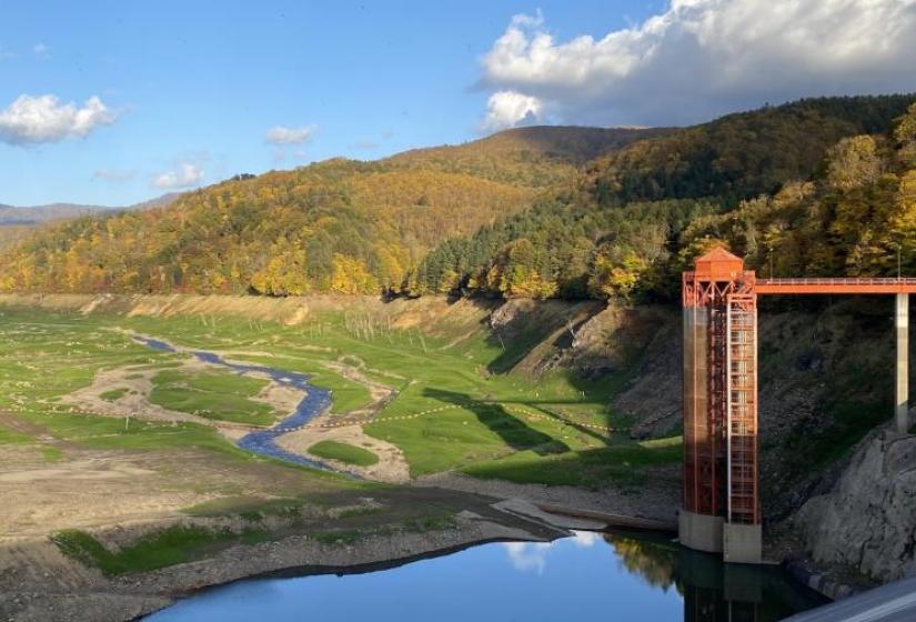 An empty damn with red pump tower to the right