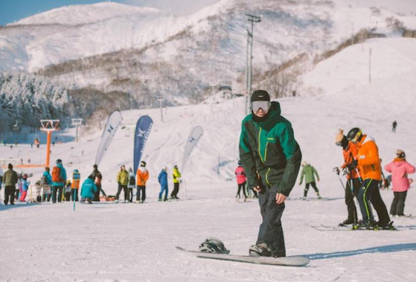 A snowboarder prepares for action at the base of a ski slope