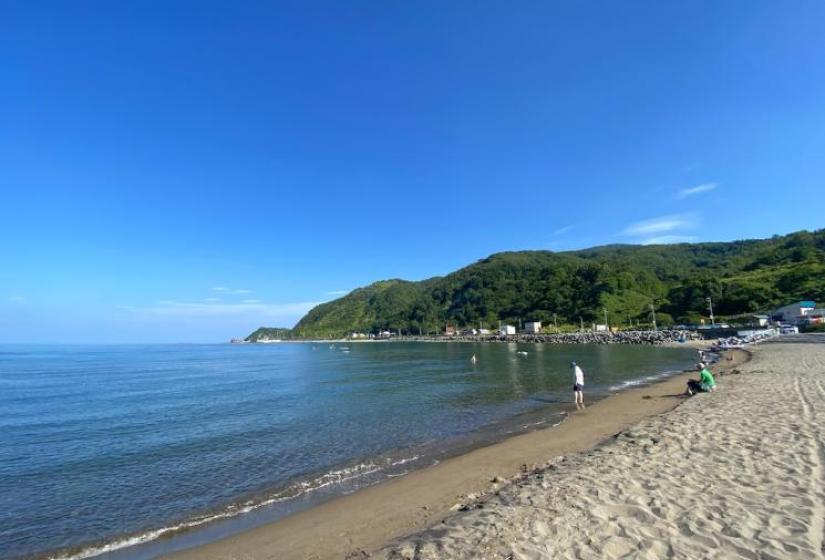 A sandy beach with still waters and blue sky