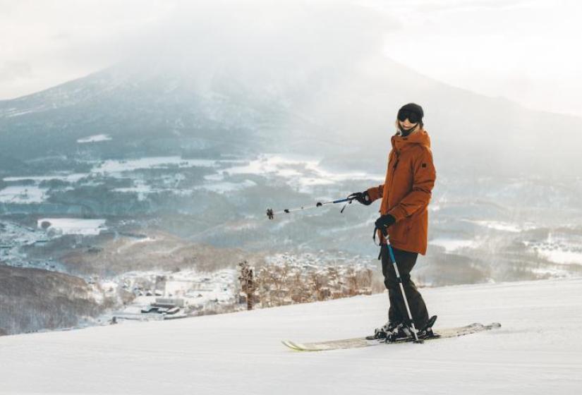 A skier points down a slope with her pole