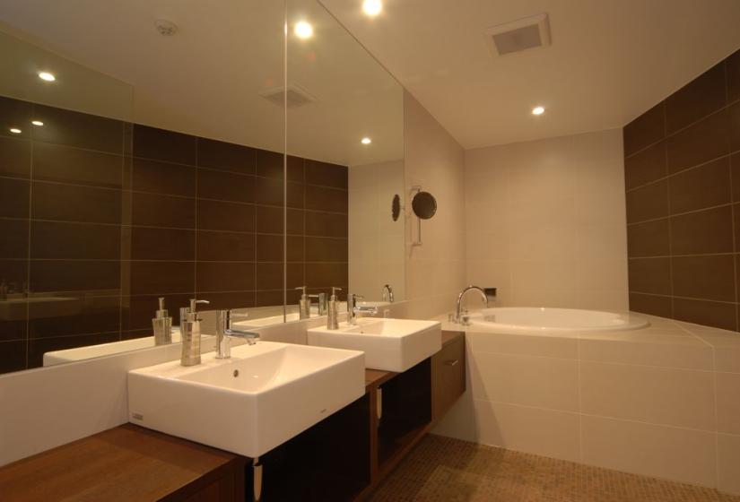 bathroom with double sink, wall size mirror and bathtub