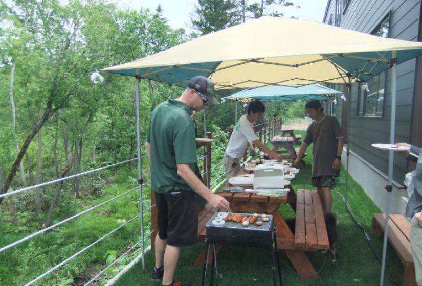 Barbeque time A man tends a bbq with bbq tables and marquee in the back ground