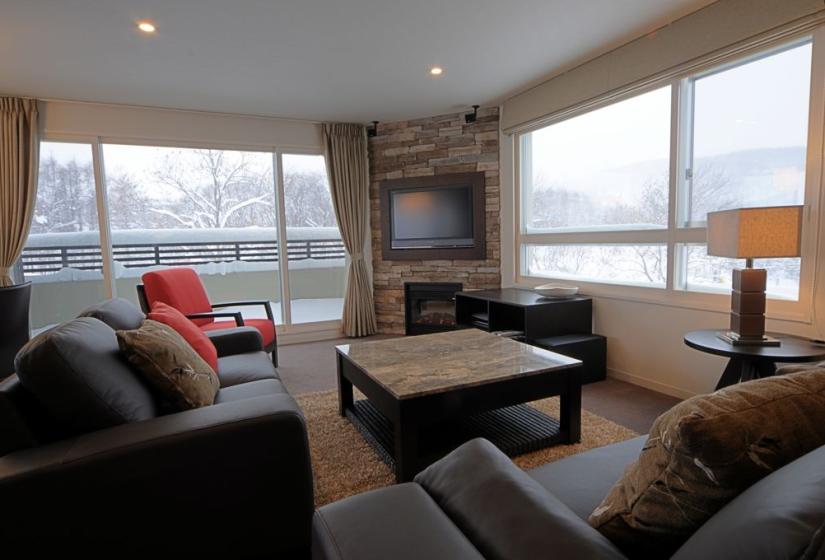 living area with stone coffee table, balcony, leather couches, tv