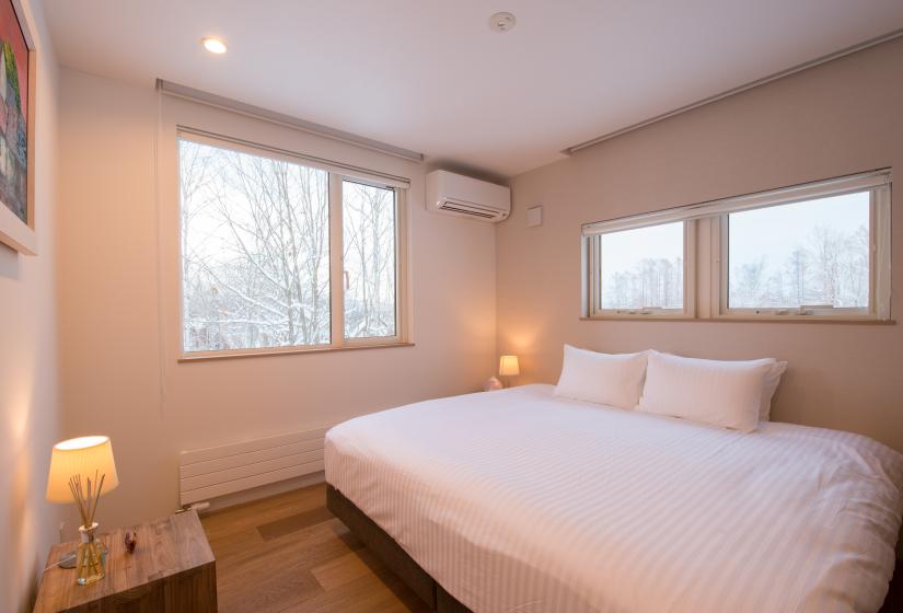 king bed with white sheets air conditioner and window