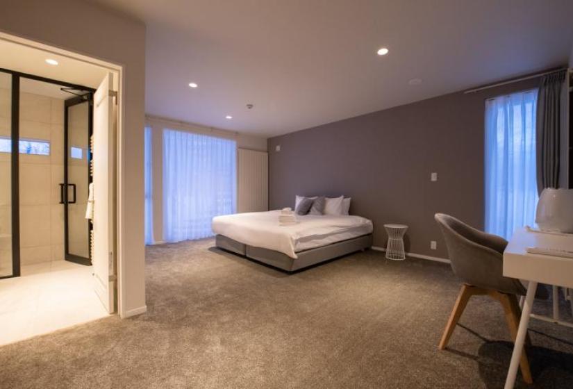 master bedroom with grey carpet and a made double bed.