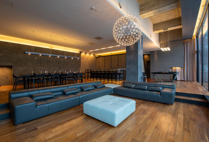 A black lounge suite with round chandelier above.