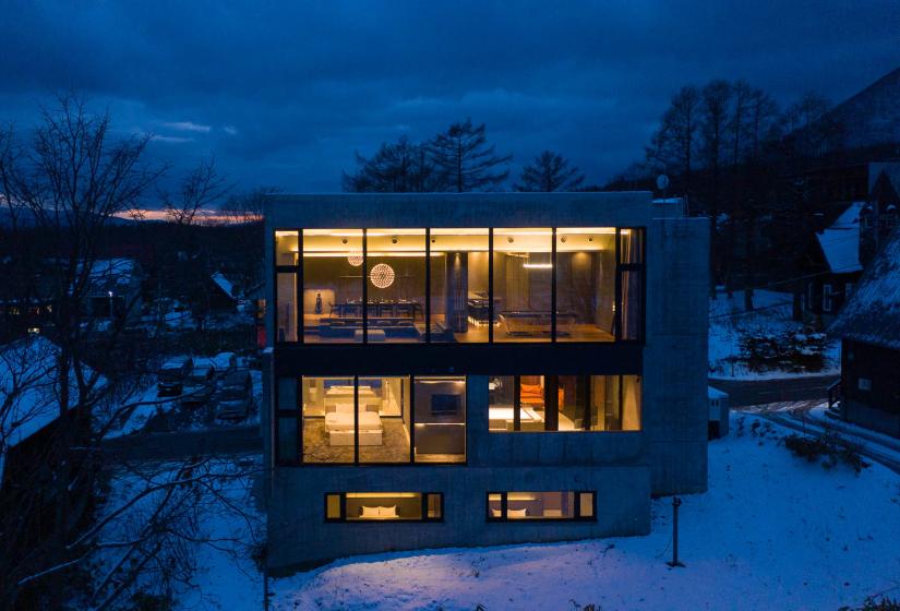 A large 3 story concrete home building lit up at night.