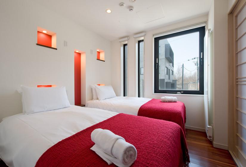 twin bedroom with red covers and folded towels