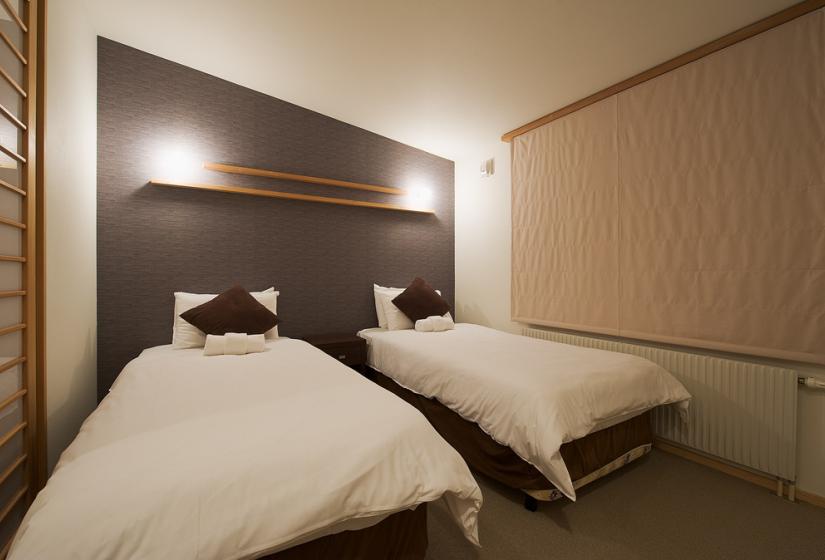 2 single white beds against a brown feature wall