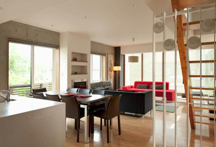 living area with red couch, table, stairs and large windows